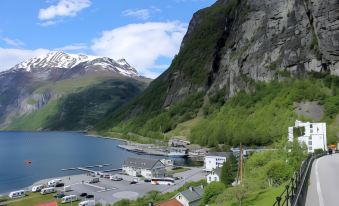 a picturesque view of a fjord surrounded by mountains , with a small town in the distance at Havila Hotel Geiranger