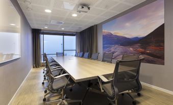 a long conference table with chairs and a large mural of mountains in the background at Scandic Narvik