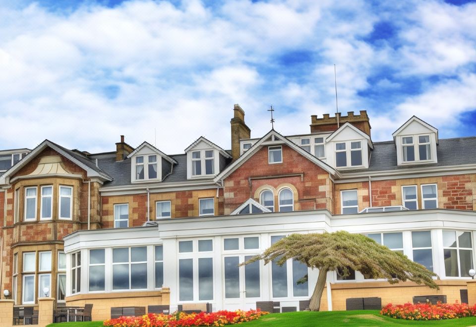 a large building with a green lawn in front of it and tall windows on the side at Seamill Hydro Hotel