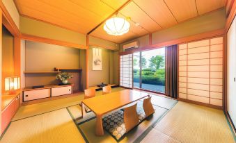 a modern japanese - style room with wooden flooring , tatami mats , and a large window overlooking a garden at Kochi Hotel