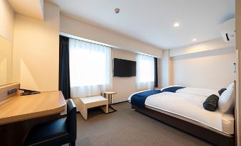 a modern hotel room with a large bed , desk , and tv , as well as a desk in the corner at Just Inn Matsusaka Station
