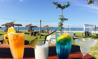 a wooden table with four colorful drinks , including orange juice and blue beverages , placed on it at Palm Beach Resort & Spa