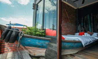 a boat on a deck with a bed and plants , reflected in a mirror of a building at The Happy 8 Retreat @ Kuala Sepetang