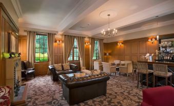 a spacious living room with multiple couches , chairs , and tables arranged in various positions , creating a comfortable atmosphere at Nunsmere Hall Hotel