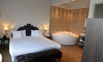 a modern bedroom with a large bed , a bathtub in the corner , and a toilet next to it at Fletcher Hotel - Restaurant Nautisch Kwartier