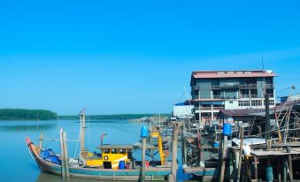 a harbor with several boats docked , and a restaurant building in the background under a clear blue sky at The Happy 8 Retreat @ Kuala Sepetang