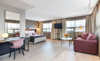 a modern hotel room with a large bed , couch , and dining table in the living area at Quality Hotel Fredrikstad