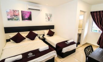 a hotel room with two beds , each bed having white sheets and maroon pillows , along with a wooden nightstand and white towel at Hotel Lavender Senawang