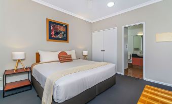 a modern bedroom with a large bed , white bedding , and a tv on the wall , along with a bathroom in the background at Comfort Inn & Suites Karratha