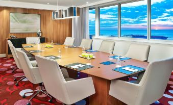 a conference room with a large table surrounded by white chairs and blue place mats at Courtyard Cleveland Elyria