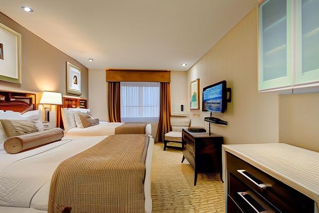 a hotel room with two beds , a desk , and a tv , along with a window and a chair at Red Lion Inn and Suites Victoria