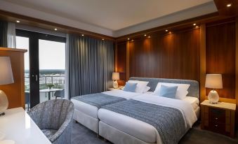 a hotel room with two twin beds , a chair , and a window overlooking the city at Maritim Hotel Darmstadt