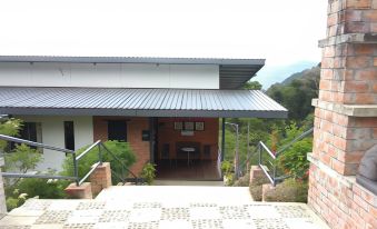 a house with a red brick exterior and a metal roof is surrounded by greenery at AYANA Holiday Resort