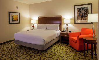 a hotel room with a bed , two orange armchairs , and a framed picture on the wall at Hilton Garden Inn Uniontown