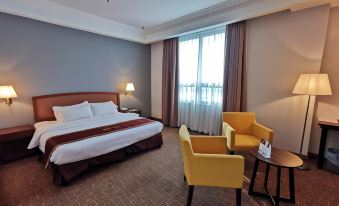 a hotel room with a king - sized bed , two yellow chairs , and a window overlooking the city at Classic Hotel Muar