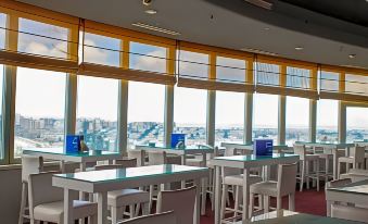 a dining room with white tables and chairs , along with a view of the city outside at Tunis Grand Hotel