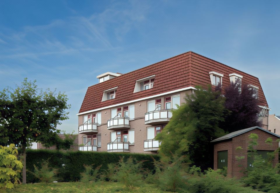 a large apartment building with multiple balconies , situated next to a green garden and under a clear blue sky at Fletcher Hotel Restaurant de Gelderse Poort