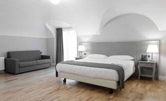 a large bed with a gray and white comforter is in the center of a room with wooden floors at Hotel de Ville