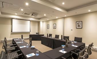 a conference room set up for a meeting , with chairs arranged in rows and a projector mounted on the wall at Mantra Melbourne Airport