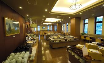 a large dining room with wooden floors and tables filled with various dishes , creating an inviting atmosphere at Route Inn Grantia Hakodate Ekimae