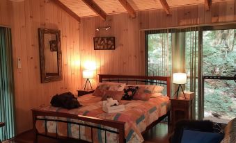 a cozy bedroom with a wooden bed , a couch , and a tv . the room has wooden walls and has a large window at Treetops Montville