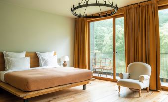 a bedroom with a large bed , wooden floors , and a sliding glass door leading to an outdoor balcony at Rooms Hotel Kazbegi