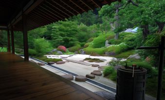 a serene japanese garden with a wooden deck and stone slabs , surrounded by lush greenery at Sotetsu Fresa Inn Kamakura-Ofuna Higashiguchi