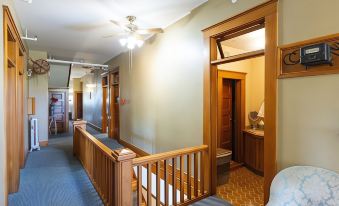 a hallway with a wooden railing and ceiling fan , leading to a room with a couch and a table at Balch Hotel