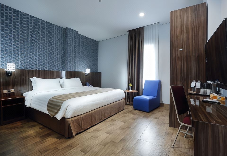 a modern hotel room with wooden floors , white bedding , and blue accent chairs , as well as a bed and a small table at Horison Express Sentani