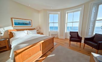 a large bedroom with a wooden floor and a bed in front of a window at A Room with A View