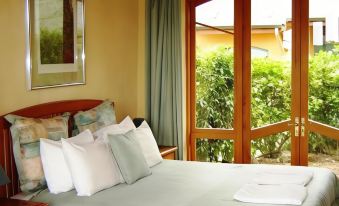 a cozy bedroom with a large bed , white sheets , and a view of the garden through a window at Earthsong Lodge