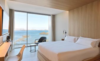 a hotel room with a large bed , wooden walls , and a view of the ocean at Noa Boutique Hotel