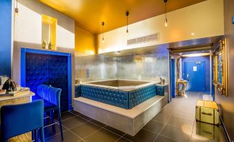 a modern bathroom with a large bathtub surrounded by blue walls , creating a spa - like atmosphere at Arthouse Hotel