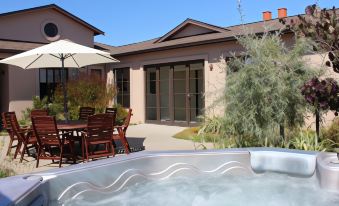 a backyard with a hot tub surrounded by patio furniture , including chairs and a dining table at The Summit Lodge