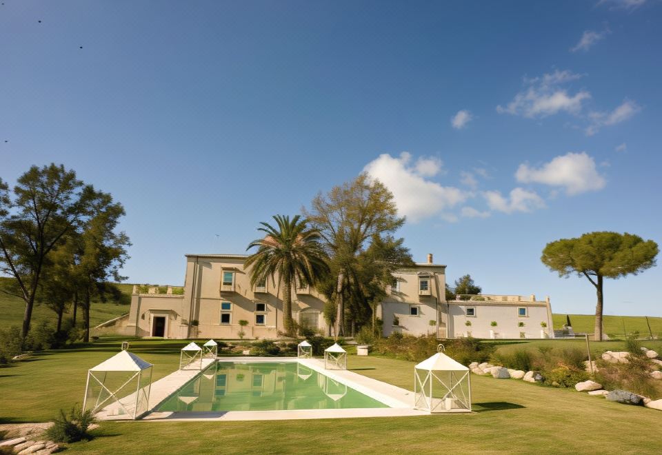 a large villa with a pool and umbrellas is surrounded by palm trees and grass at Castello Camemi
