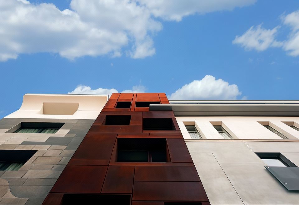 a modern building with red and brown metal panels , surrounded by other buildings under a blue sky at Hotel Continental