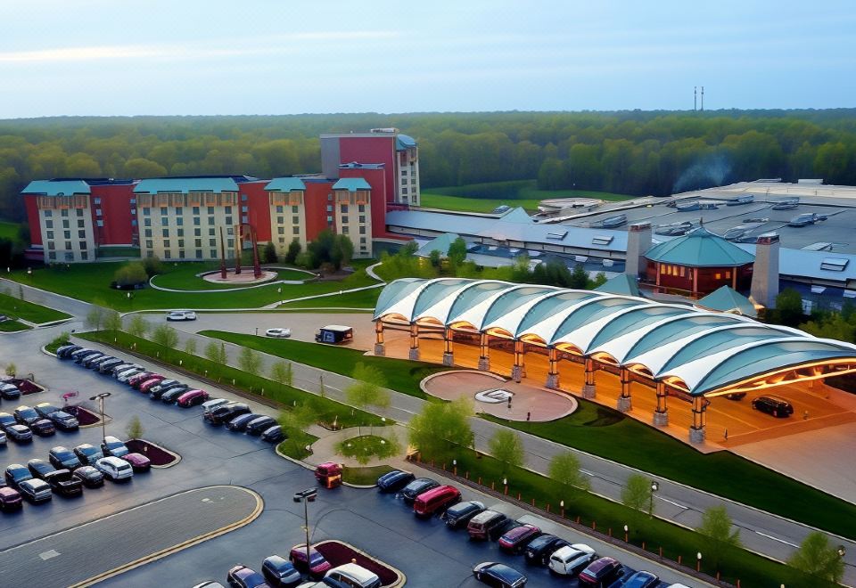 a large building with a parking lot and trees in front of it , and several cars parked on the side of the road at Four Winds Casino Resort – New Buffalo