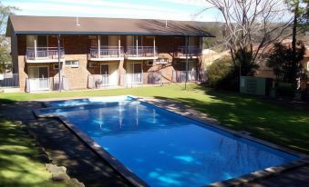 an outdoor swimming pool surrounded by a brick building , with a hot tub in the background at Waterview Gosford Motor Inn