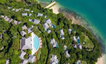 aerial view of a resort on a beach , surrounded by trees and water , with multiple buildings in the background at Six Senses YAO Noi