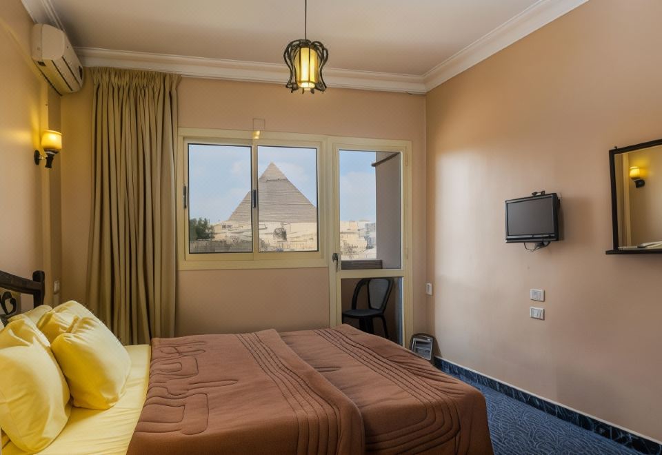 a hotel room with a large bed , a television , and a window overlooking the pyramids at Pyramids View Inn