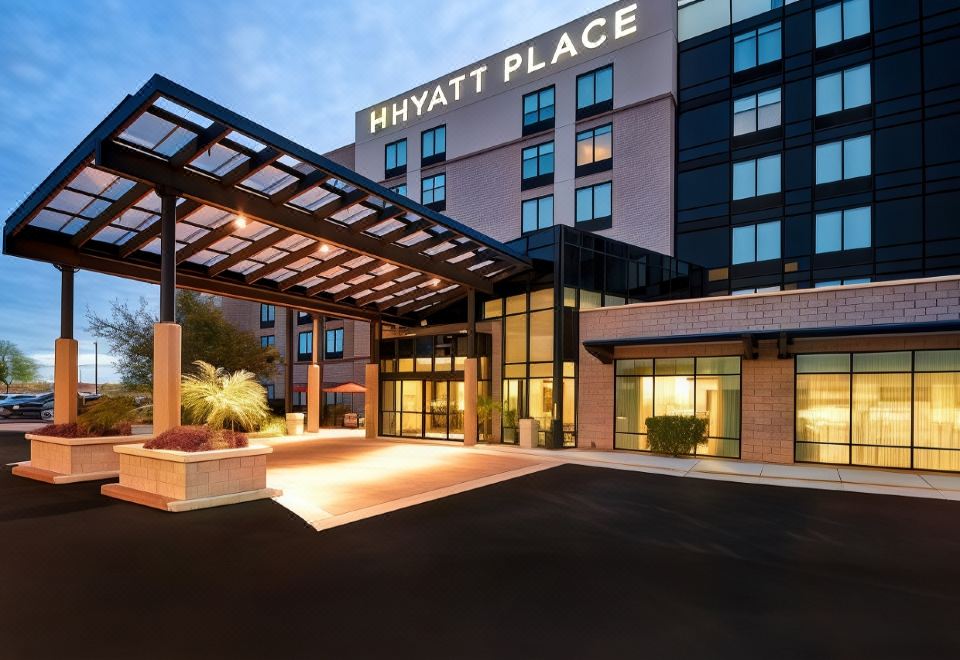 a hyatt place hotel entrance with its name displayed above the doorway , and a car parked in front of it at Hyatt Place Fresno
