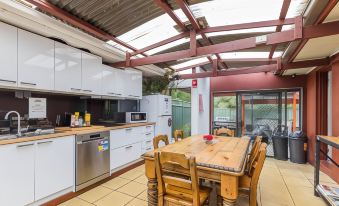 a modern kitchen with white cabinets , a wooden dining table , and a stainless steel oven at Black Forest Motel