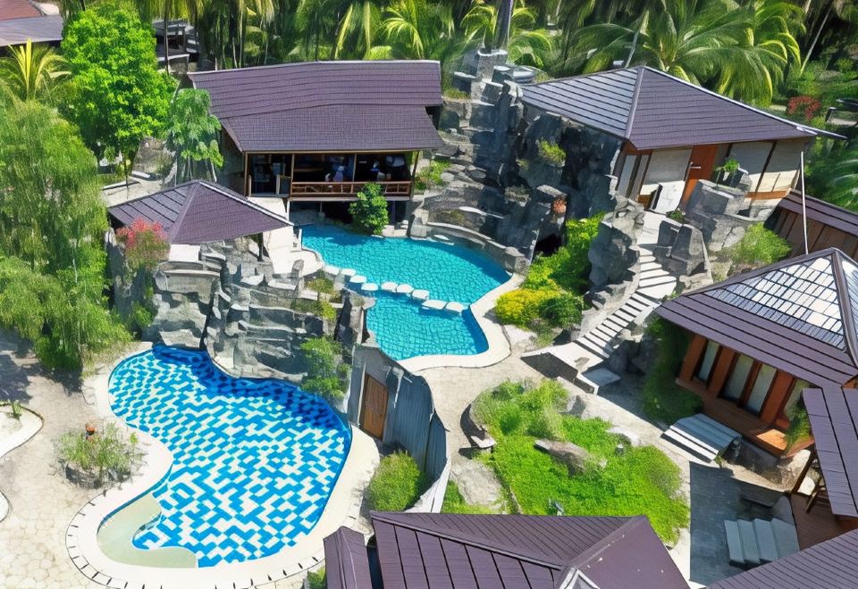 an aerial view of a resort with a large pool surrounded by palm trees and a house at Tasik Ria Resort