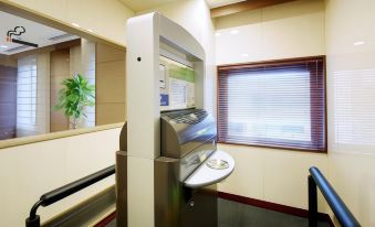 a modern bank teller office with a cash dispenser , window blinds , and a sign on the wall at Daiwa Roynet Hotel Hachinohe