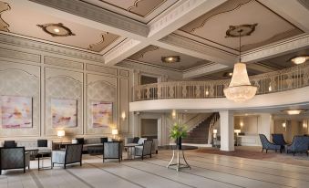 a large , elegant hotel lobby with high ceilings , multiple couches , and chairs arranged around a central table at Hilton St. Louis Frontenac