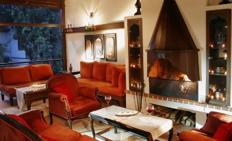 a cozy living room with a fireplace , orange furniture , and wine glasses on a table at Aspen Hotel
