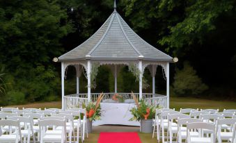 a white gazebo with a red carpet and chairs set up for an outdoor wedding ceremony at Alton House Hotel