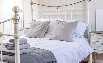 a white metal bed with two pillows and a blanket on top of it , in a bedroom at The Golden Key