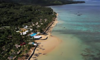 aerial view of a sandy beach surrounded by trees , with a large body of water in the background at Fiji Hideaway Resort and Spa