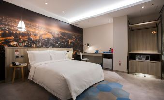 a large bed with white sheets and pillows is in a room with a blue carpet at Airline Inn Kaohsiung Station